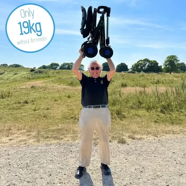 Elderly man holding transportable CarbonLite mobility scooter above his head