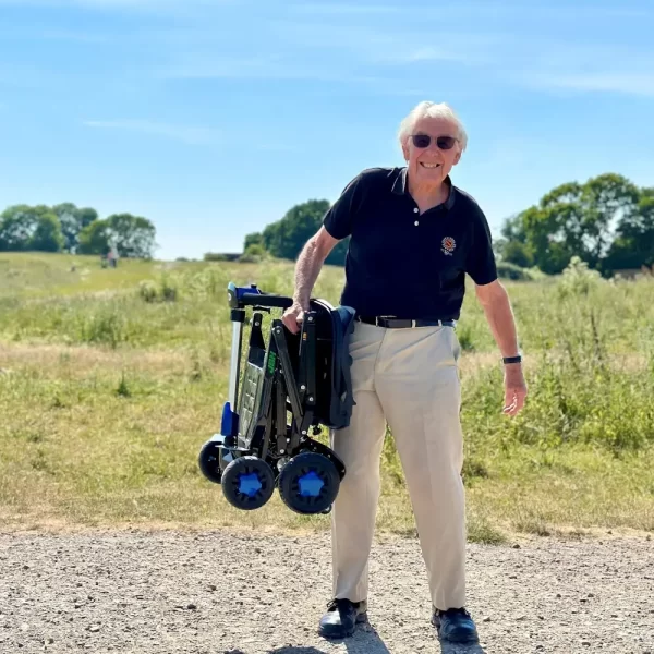 Older gentleman carrying the easy to lift "CarbonLite" carbon fibre disability scooter with one arm